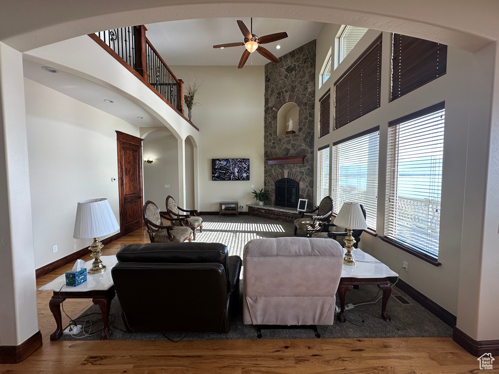 Living room with arched walkways, a towering ceiling, ceiling fan, and wood finished floors