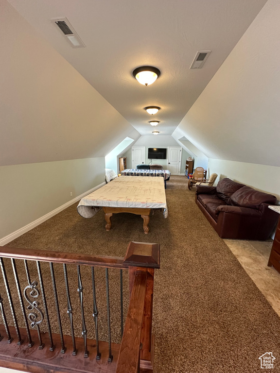 Recreation room featuring carpet flooring, visible vents, and vaulted ceiling