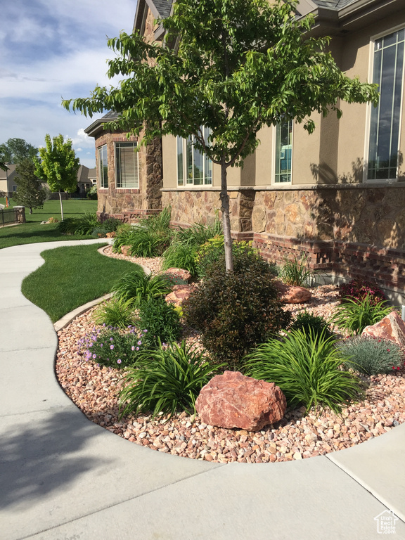 View of home\\\'s exterior featuring stone siding, a lawn, and stucco siding