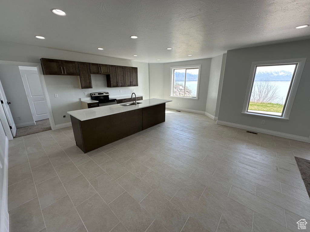 Kitchen with a sink, light countertops, dark brown cabinetry, and stainless steel range with electric stovetop