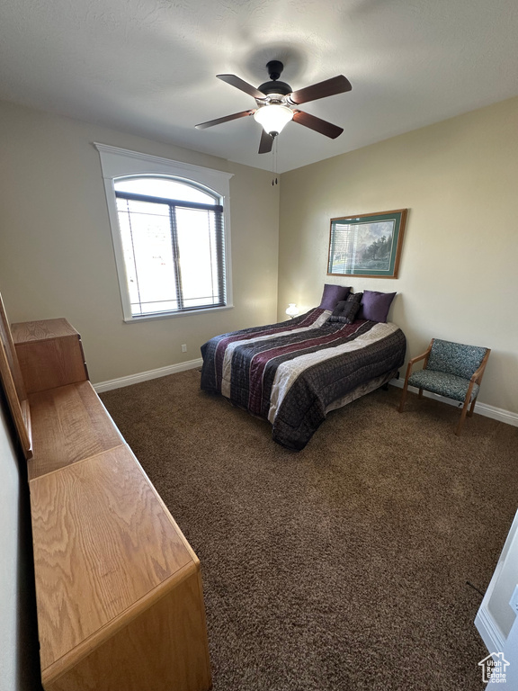 Bedroom featuring baseboards, a ceiling fan, and dark colored carpet