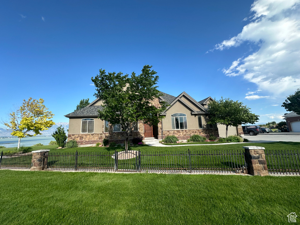 View of front facade with a front yard, stucco siding, and stone siding