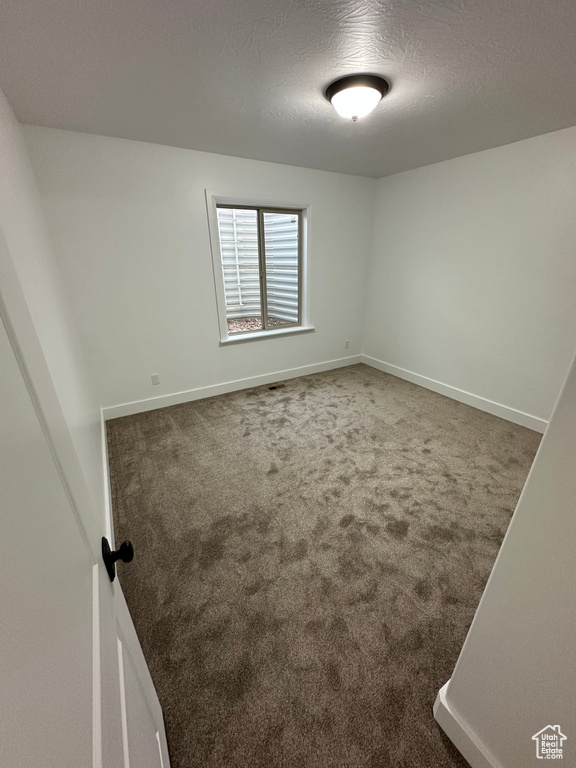 Carpeted spare room with baseboards and a textured ceiling