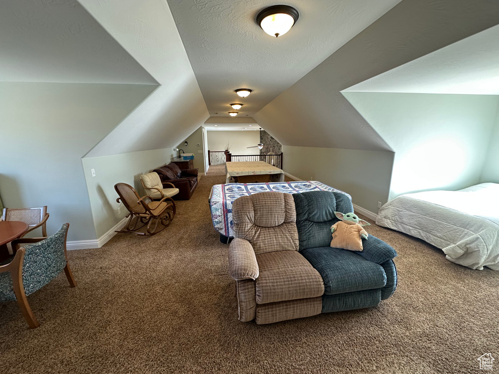 Carpeted bedroom with a textured ceiling, baseboards, and lofted ceiling