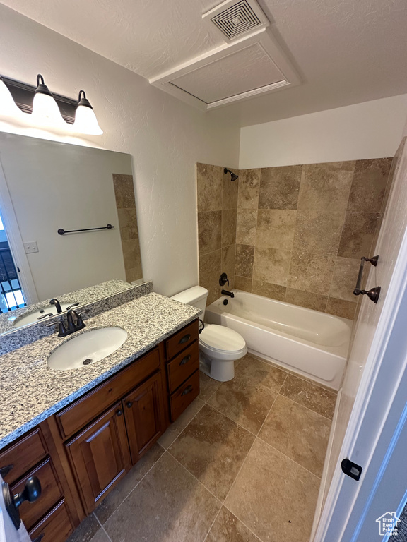 Bathroom featuring vanity, a textured wall, shower / bath combination, toilet, and visible vents