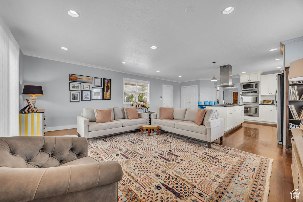 Living room featuring ornamental molding, baseboards, recessed lighting, and wood finished floors