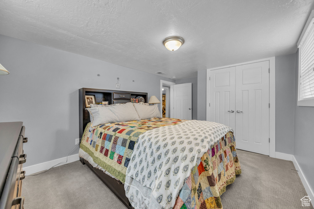 Carpeted bedroom with a closet, visible vents, a textured ceiling, and baseboards