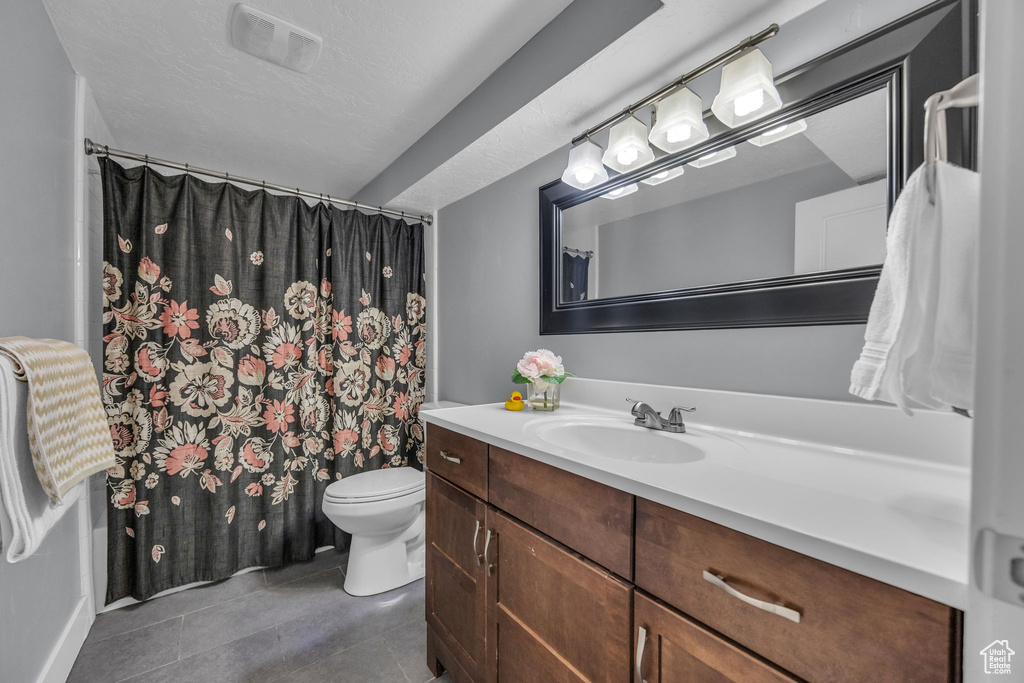 Full bath featuring visible vents, a shower with shower curtain, toilet, vanity, and tile patterned floors