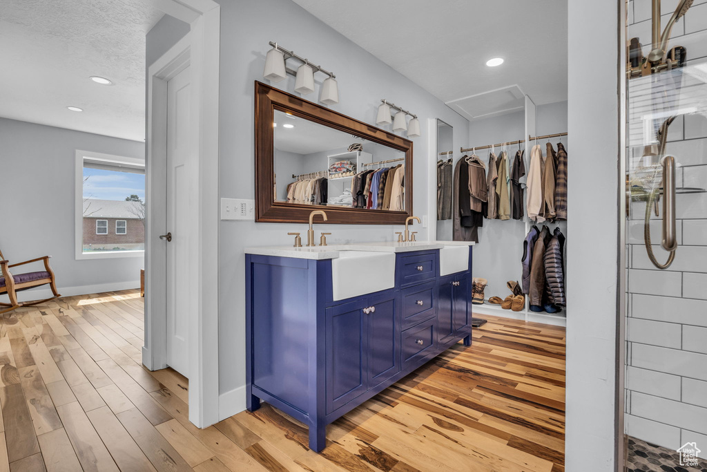 Bathroom featuring a spacious closet, double vanity, a sink, and wood finished floors