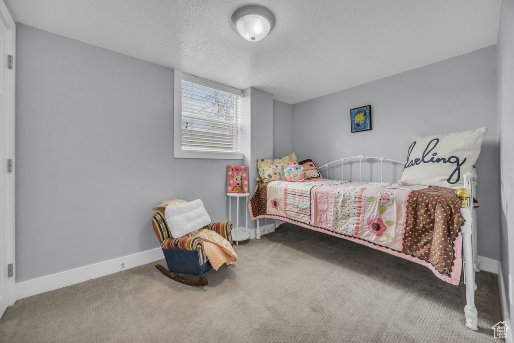 Carpeted bedroom featuring a textured ceiling and baseboards