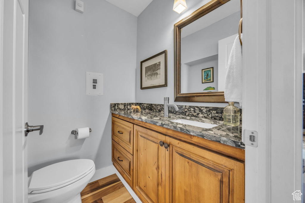 Bathroom with toilet, vanity, wood finished floors, and baseboards