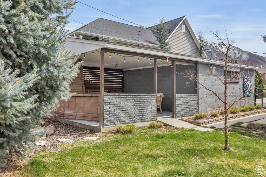 Exterior space featuring a sunroom, a shingled roof, and a lawn