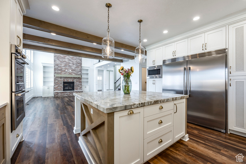 Kitchen with built in appliances, open floor plan, dark wood-style floors, white cabinets, and beam ceiling