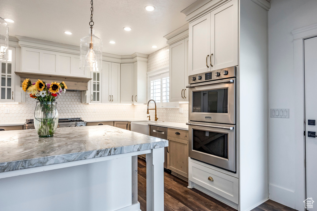 Kitchen with stainless steel double oven, dark wood finished floors, recessed lighting, decorative backsplash, and glass insert cabinets