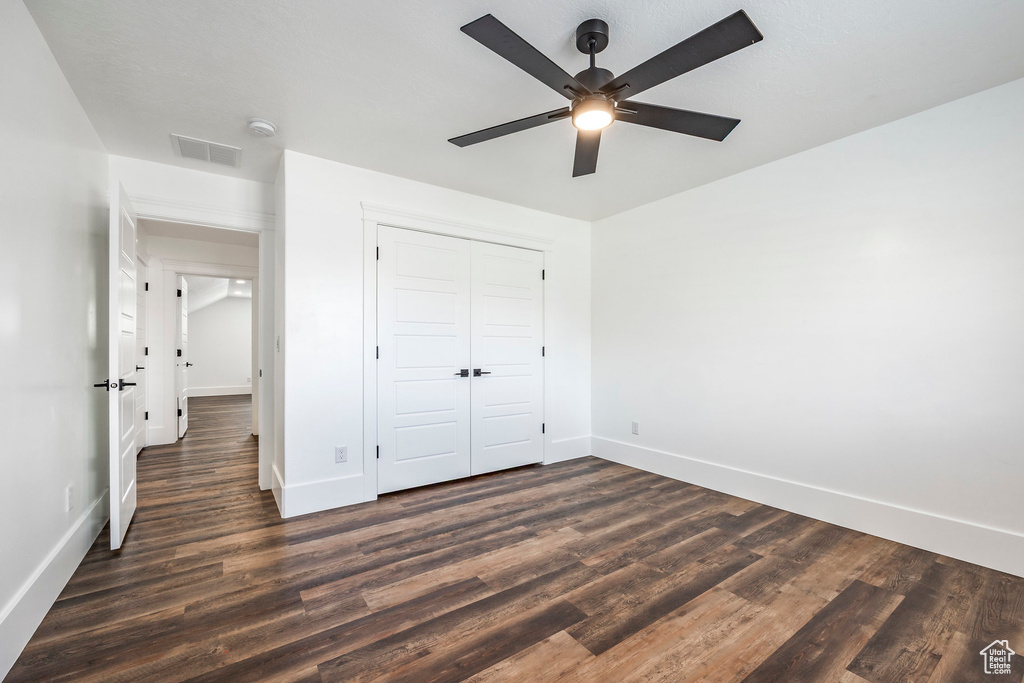 Unfurnished bedroom with dark wood finished floors, a closet, and a ceiling fan