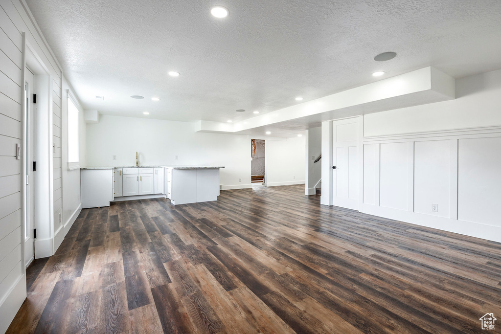 Unfurnished living room featuring a textured ceiling, dark wood-style flooring, stairway, and recessed lighting