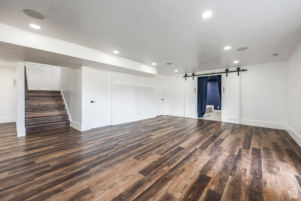 Unfurnished living room with wood finished floors, a barn door, stairs, and recessed lighting