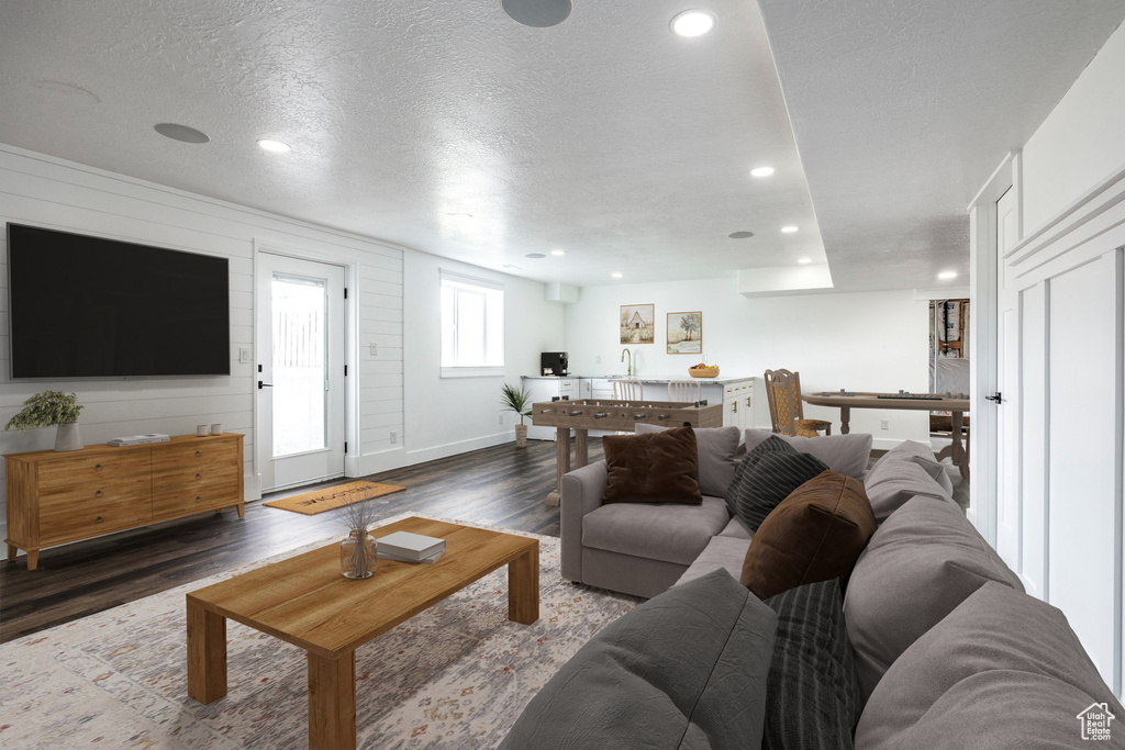 Living room with wood finished floors, a textured ceiling, and recessed lighting