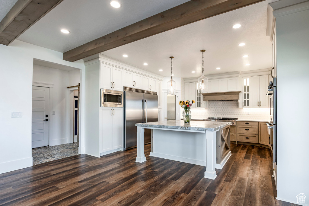 Kitchen with built in appliances, a center island, beam ceiling, backsplash, and a kitchen breakfast bar