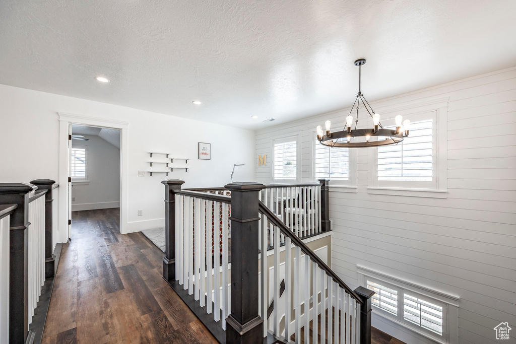 Corridor with an upstairs landing, a chandelier, dark wood-style floors, and recessed lighting