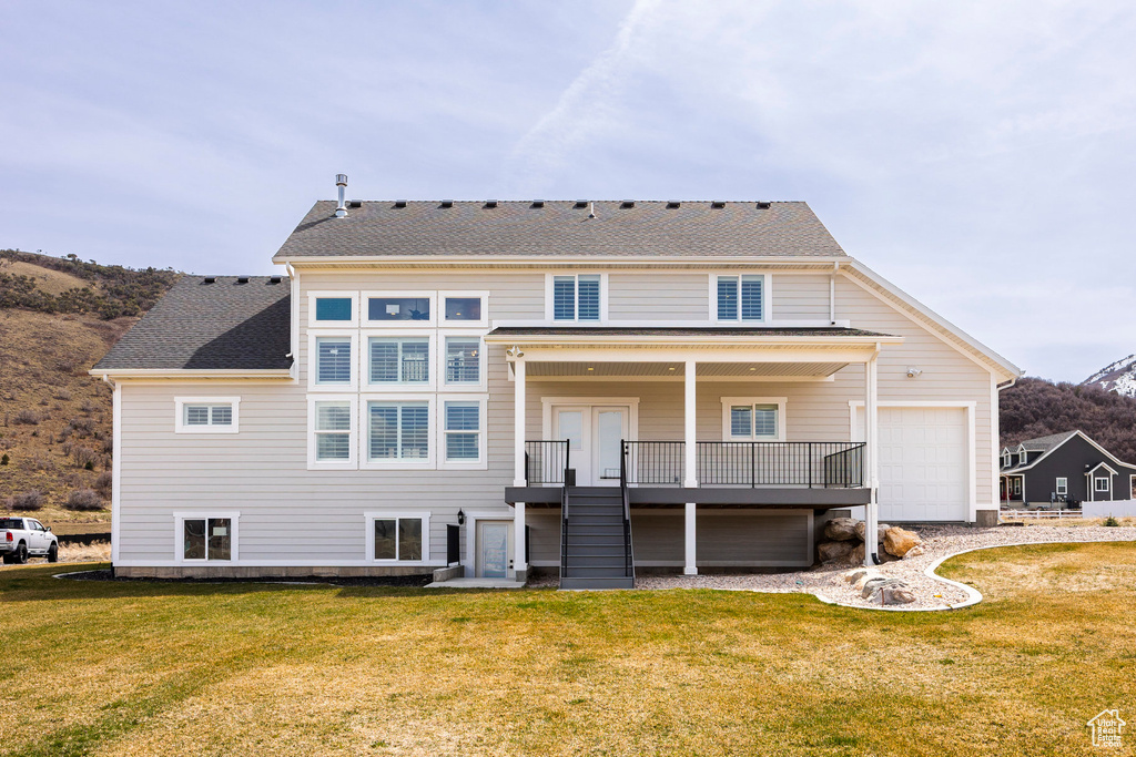 Rear view of property with stairs, a yard, a mountain view, and a shingled roof