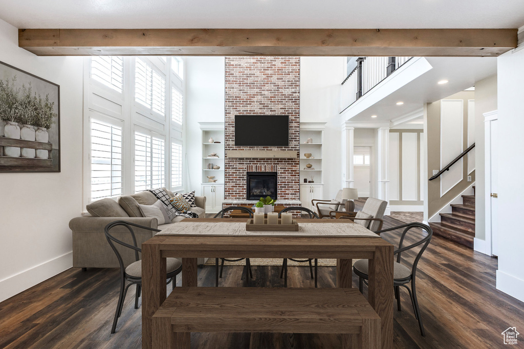 Dining room with a fireplace, recessed lighting, dark wood-style flooring, a towering ceiling, and stairs