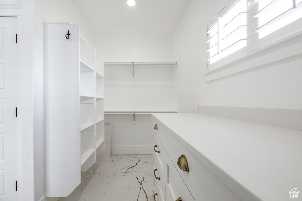 Spacious closet featuring light marble finish flooring