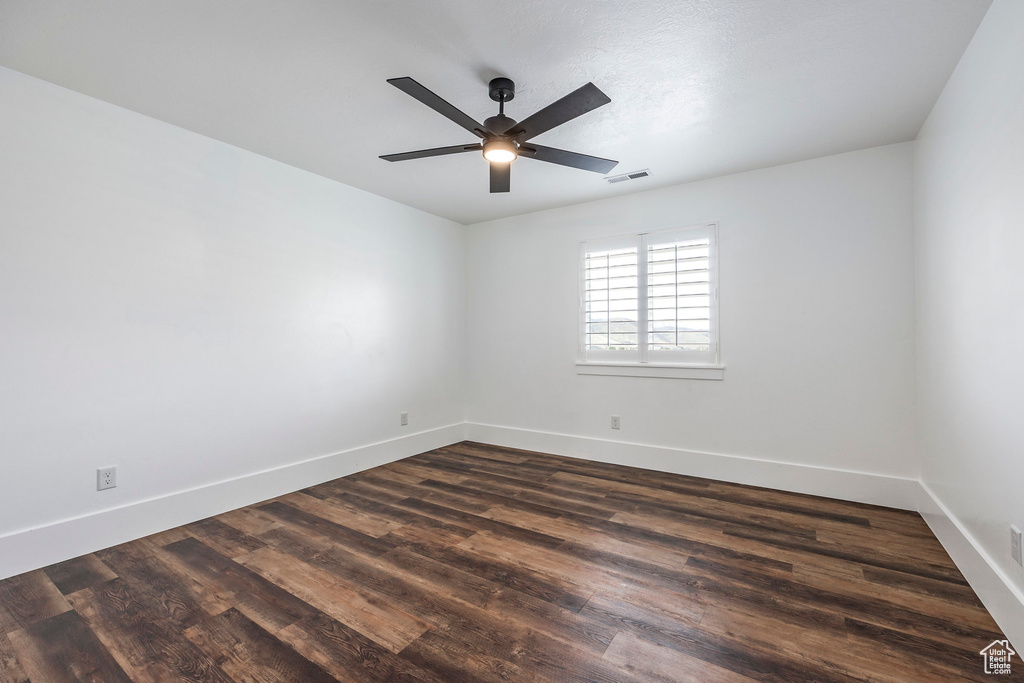 Empty room with dark wood-style floors and a ceiling fan