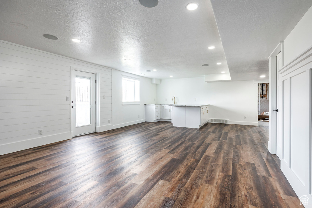 Unfurnished living room featuring dark wood-style floors, recessed lighting, and a textured ceiling