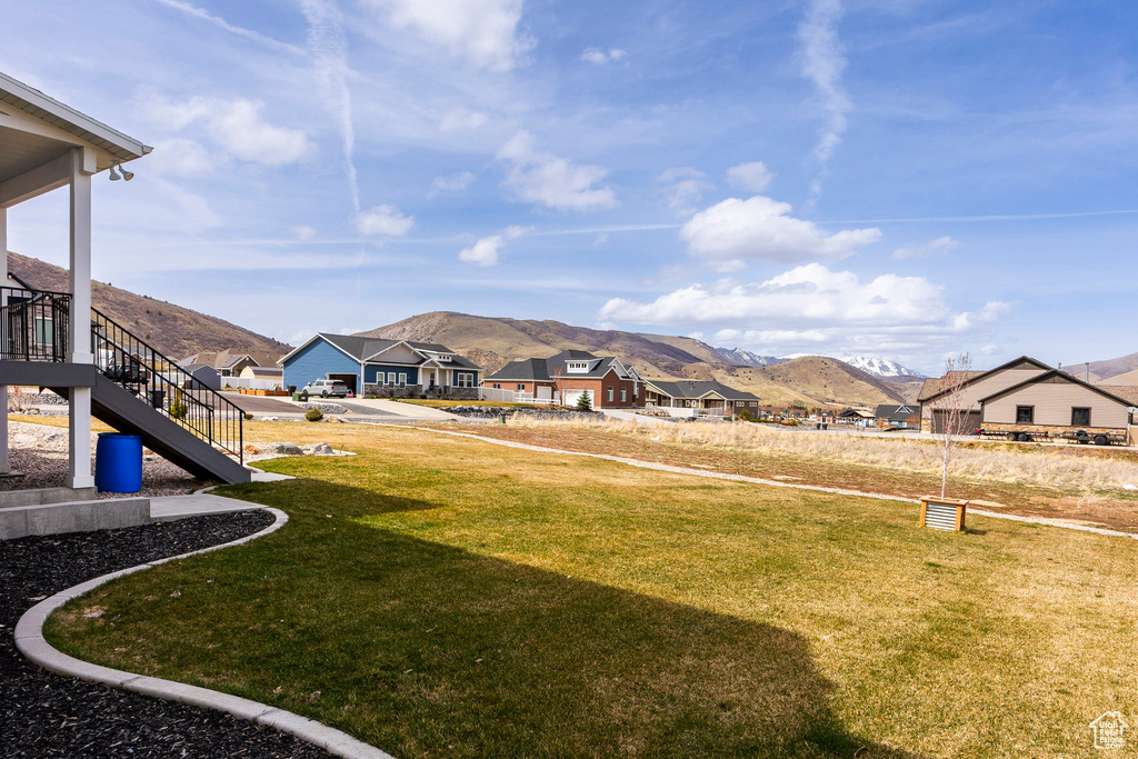 View of grassy yard featuring a mountain view, stairway, and a residential view