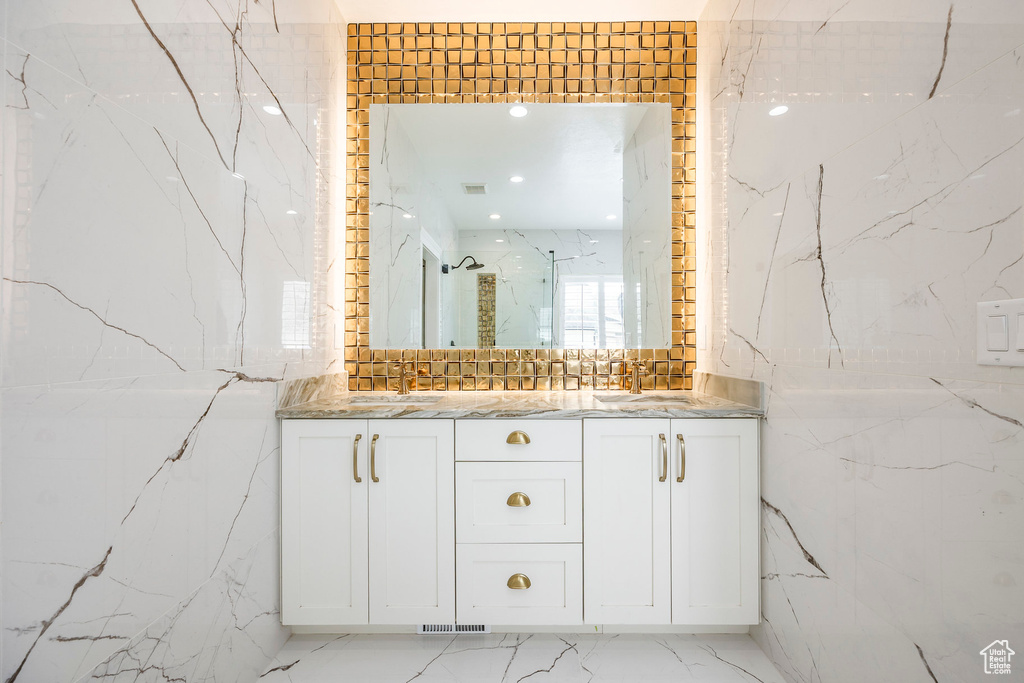 Full bathroom featuring double vanity, marble finish flooring, tile walls, and a marble finish shower