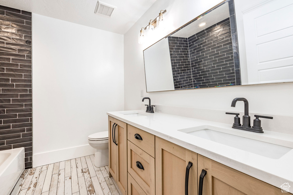 Full bath featuring double vanity and wood finished floors