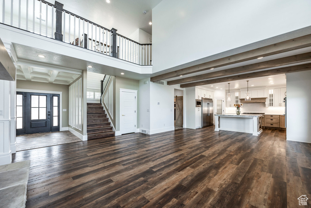 Unfurnished living room featuring stairs, dark wood-type flooring, beam ceiling, and recessed lighting