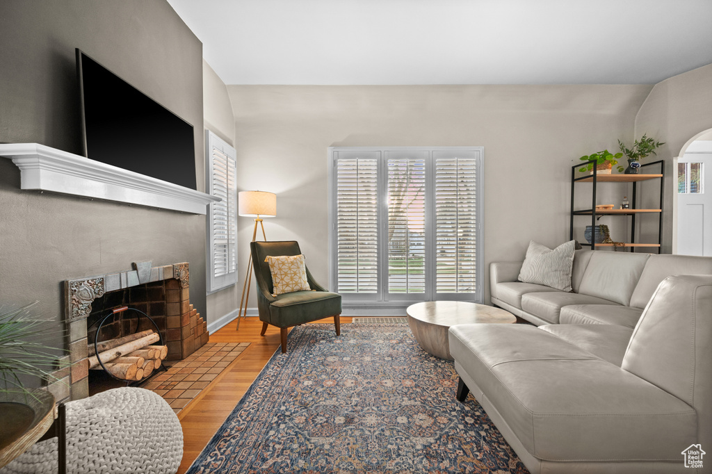 Living room featuring wood finished floors, a tiled fireplace, and baseboards