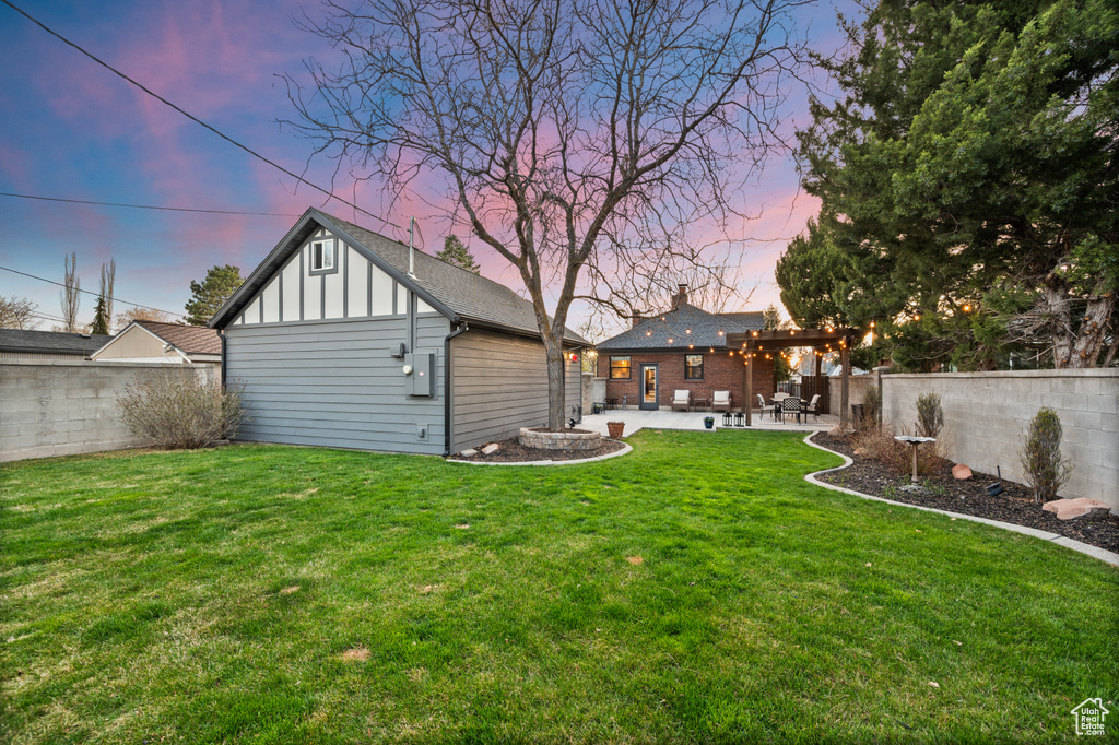 Yard at dusk with an outbuilding, a fenced backyard, and a patio area