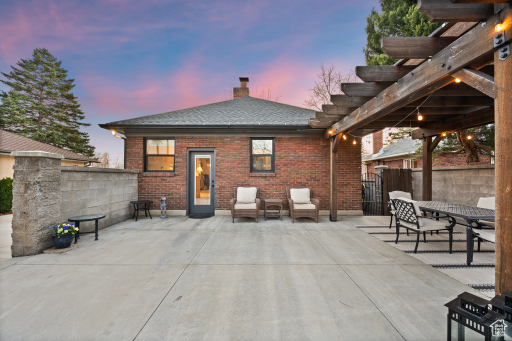 Patio terrace at dusk with a pergola and fence