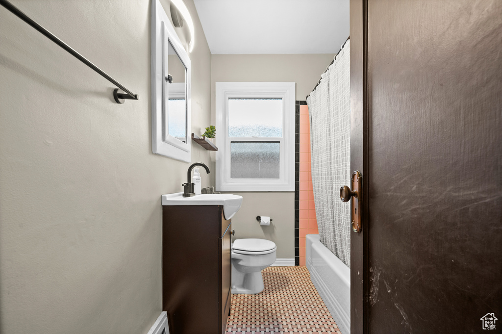 Full bathroom featuring toilet, vanity, baseboards, and shower / tub combo with curtain
