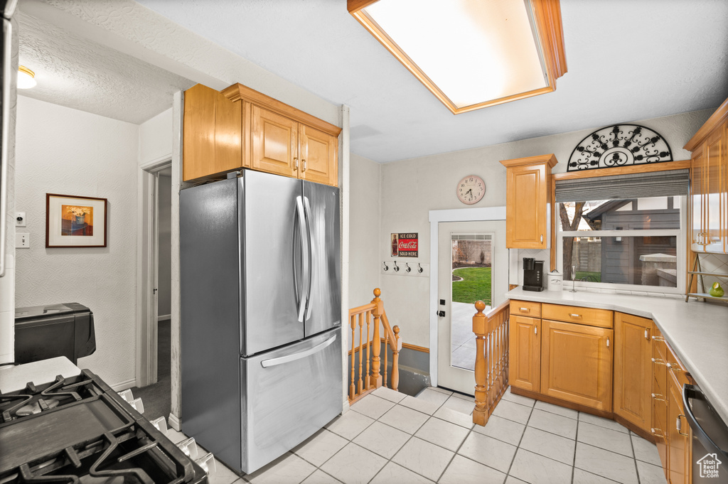 Kitchen with light tile patterned floors, light countertops, and appliances with stainless steel finishes