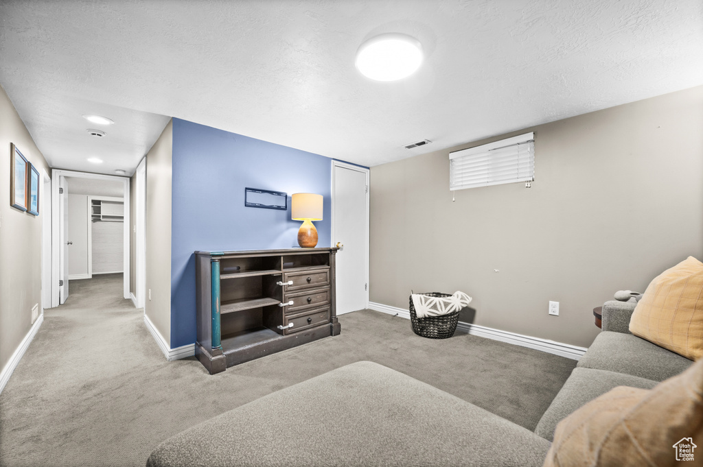 Carpeted living area featuring visible vents, baseboards, and a textured ceiling