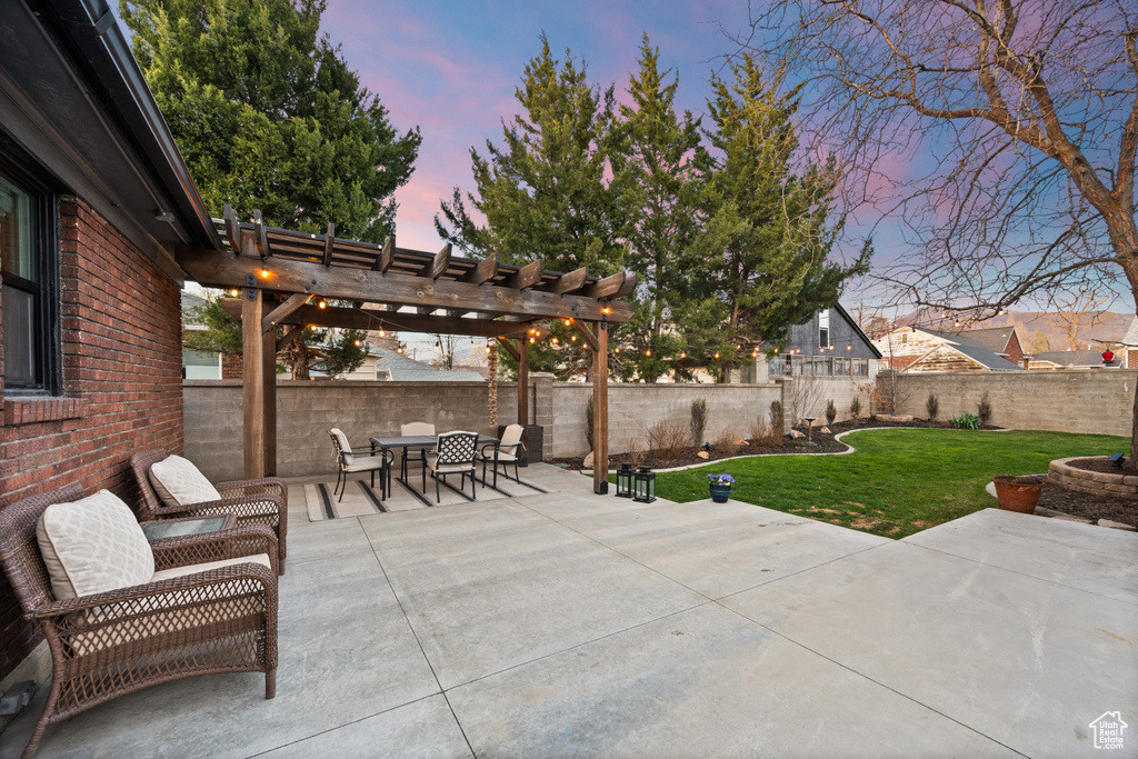 Patio terrace at dusk featuring a yard, a fenced backyard, outdoor dining space, and a pergola