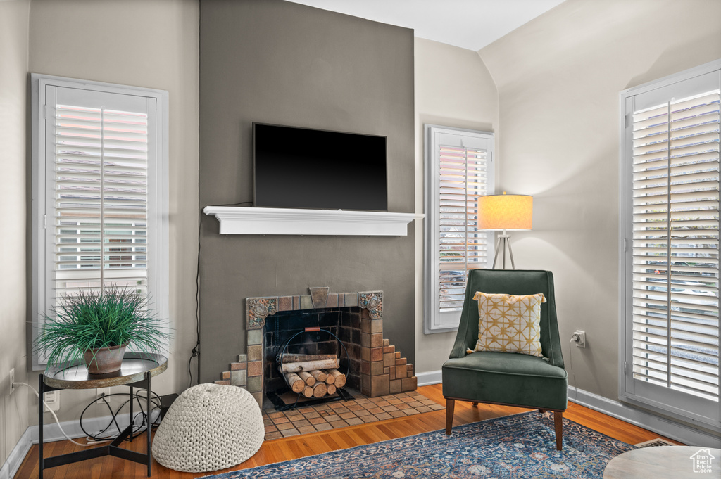 Living area featuring baseboards, vaulted ceiling, wood finished floors, and a fireplace with flush hearth