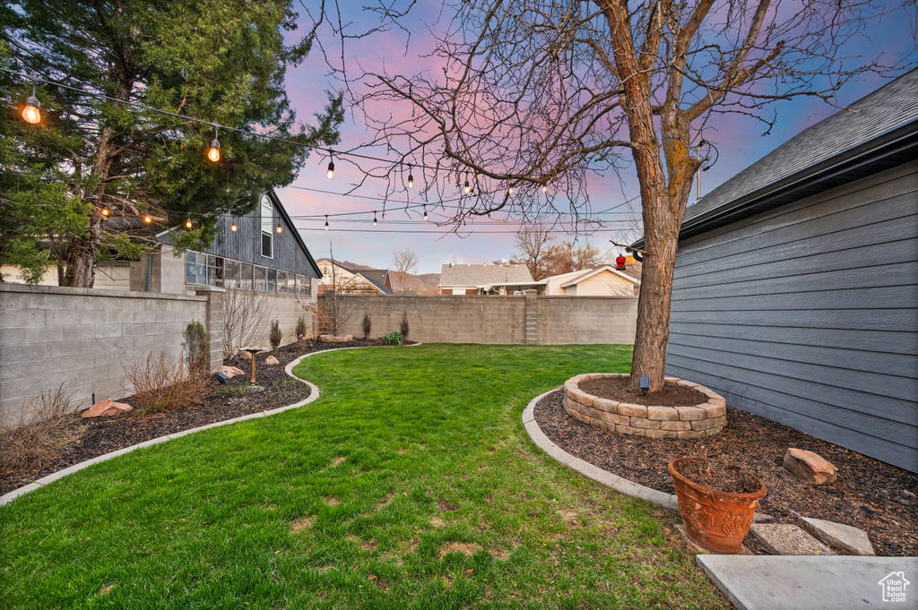Yard at dusk featuring a fenced backyard