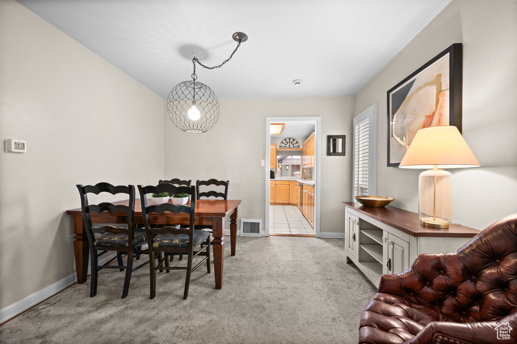 Dining space with visible vents, light colored carpet, and baseboards