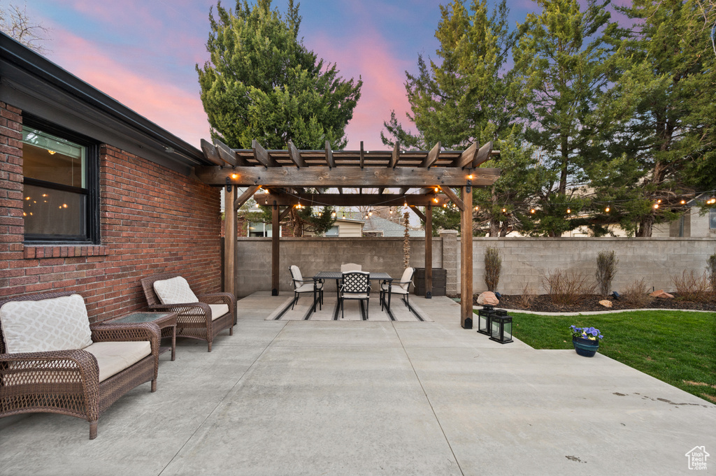 Patio terrace at dusk featuring a pergola, fence, and outdoor dining space