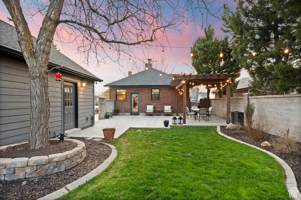 Rear view of house with a patio area, a lawn, a chimney, fence, and brick siding