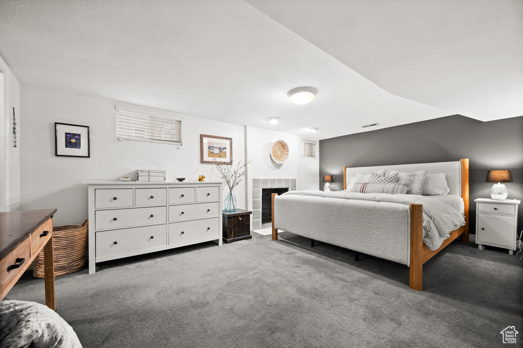 Bedroom featuring visible vents, a tiled fireplace, and carpet