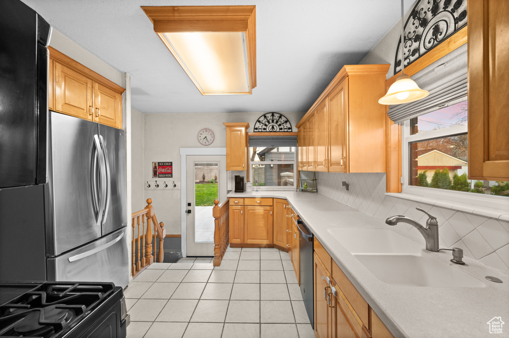 Kitchen with a sink, tasteful backsplash, light countertops, and black appliances