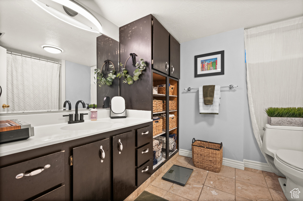 Full bathroom featuring toilet, vanity, and baseboards