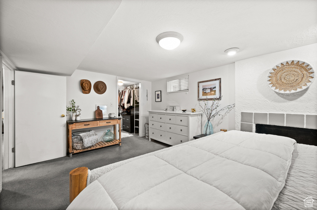Carpeted bedroom with a closet, a walk in closet, and a tile fireplace