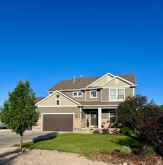 View of front of home with a porch, concrete driveway, a front yard, an attached garage, and board and batten siding